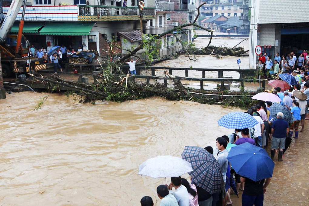 Residents look on as debris from heavy rains gathers at a bridge over a flooded river in Shitang, Guangxi. Photo: Reuters