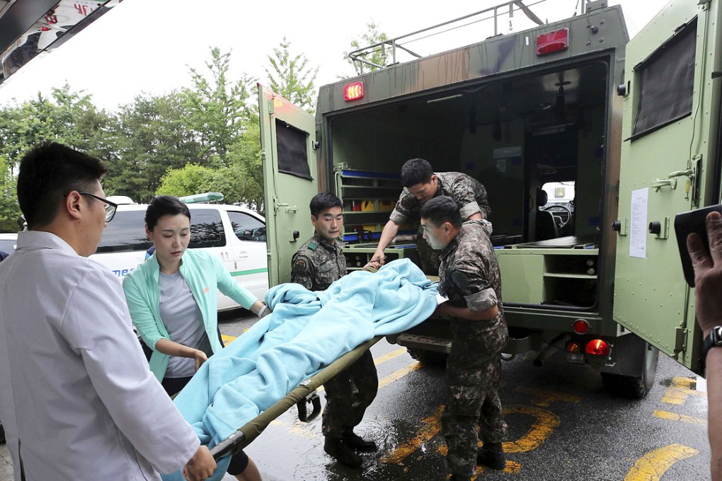 Army personnel take Sergeant Lim, who shot and killed five comrades, to hospital wrapped with a blanket. He is in a stable condition after an apparent suicide bid. Photo: Reuters