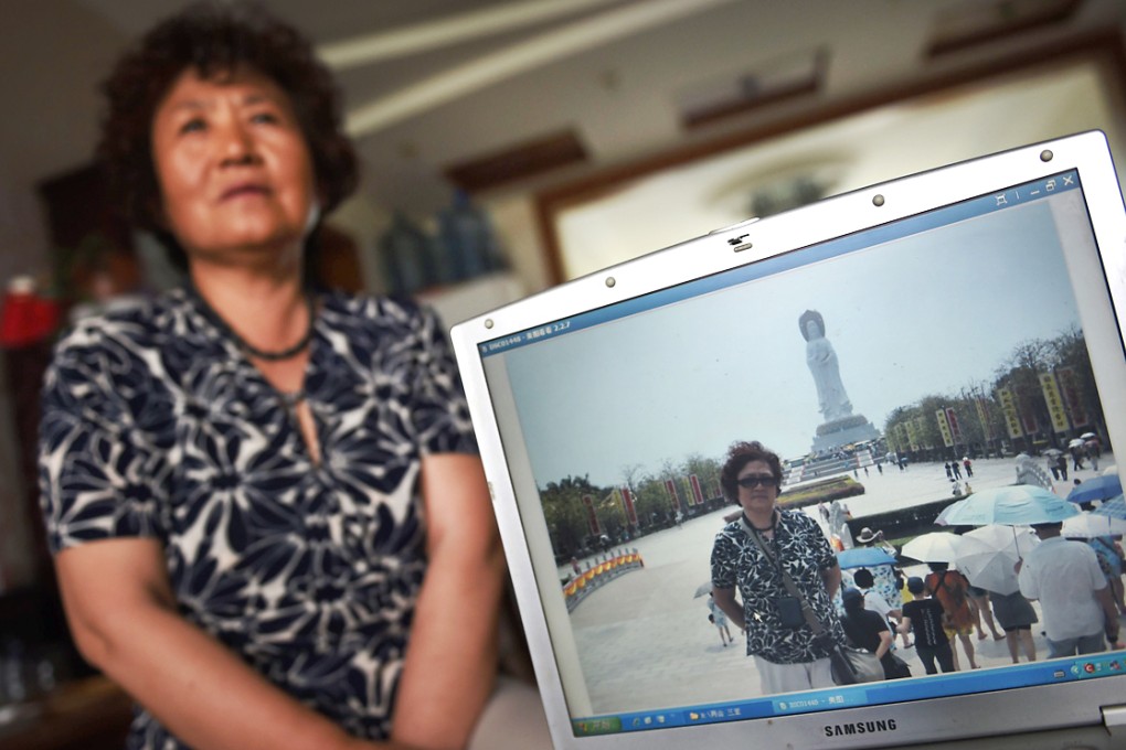 Activist Xu Xiangyu in her Beijing apartment, with a photo of herself posing in front of the Buddha statue at the Nanshan Temple on China's southern Hainan island, during a forced vacation in March 2011. Photo: AFP