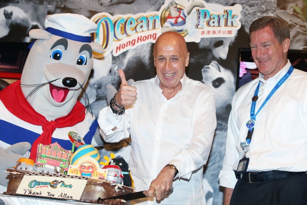 Ocean Park's mascot Whiskers presents chairman Allan Zeman with a farewell cake from management as theme park CEO Tom Mehrmann looks on. Photo: Sam Tsang