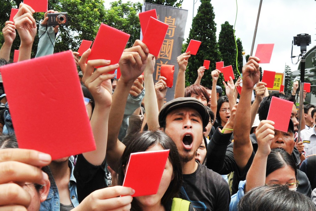Demonstrators hold up red cards to show their disapproval of Zhang Zhijun. Photo: AFP