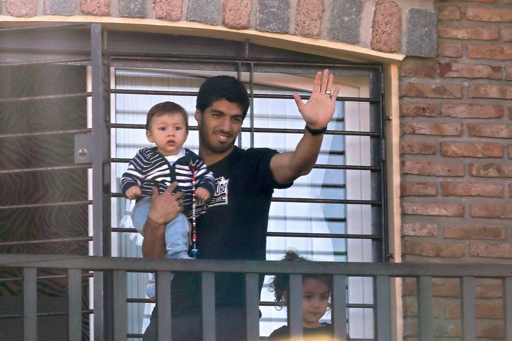 Luis Suarez, pictured with his children, waves at fans and media from his mother's home in Lagomar, near Montevideo, on Friday. Photo: AFP