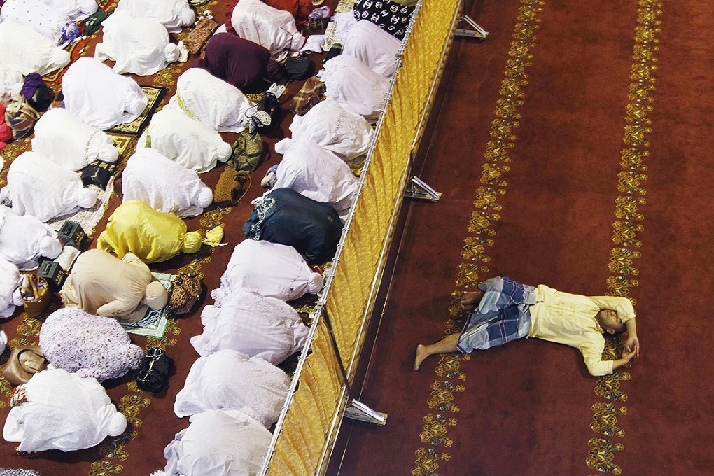 A man takes a nap as Muslim women attend an evening "tarawih" prayer session at the Great Mosque in Medan, north Sumatra, to mark the start of the holy fasting month of Ramadan. Photo: Reuters