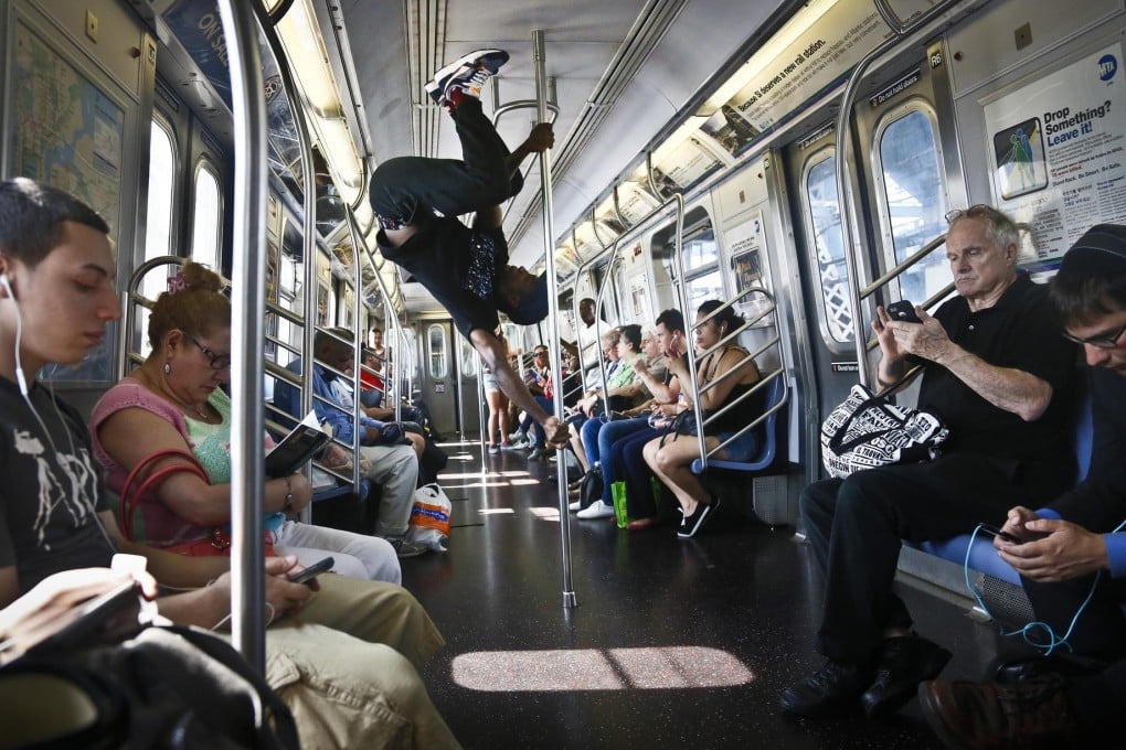 Subway performer Dashawn Martin twirls around a pole in a New York subway train as the passengers go about their business. Photo: AP