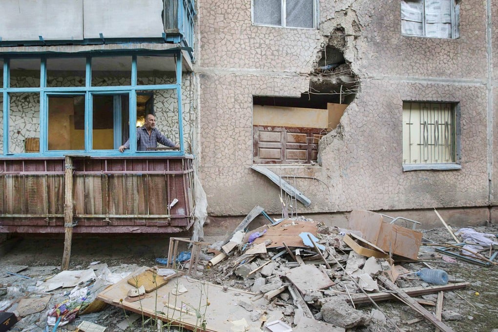 A man looks out of a window of an apartment damaged by shelling in Slaviansk. Ukraine's Poroshenko has decided to resume a military offensive against pro-Russian separatists. Photo: Reuters