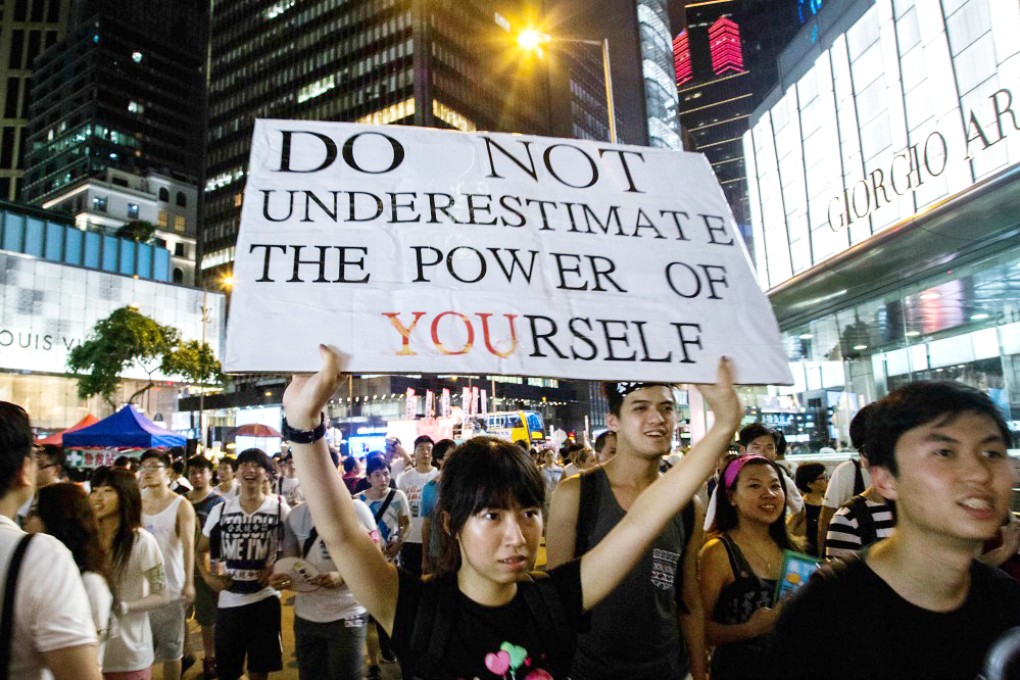 A marcher holds aloft a protest sign on Tuesday during the pro-democracy rally. Photo: Lam Yik Fei/Bloomberg
