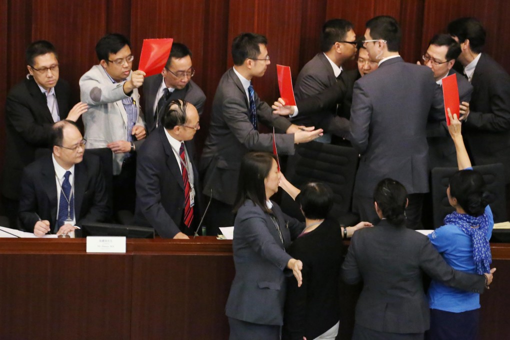 Pan-democratic lawmakers wave red cards as they crowd around chairman Ng Leung-sing at yesterday's Finance Committee meeting. Photo: Felix Wong