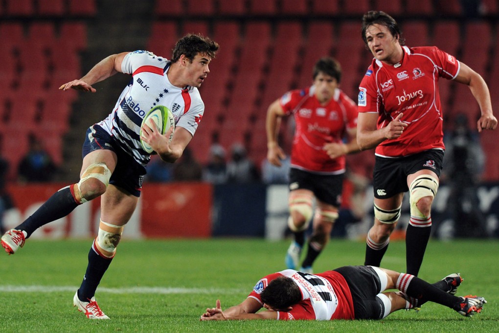 Tom English of Melbourne Rebels slips a tackle from Lions fly-half Marnitz Boshoff as lock Franco Mostert closes in. The Lions won 34-17. Photo: AFP