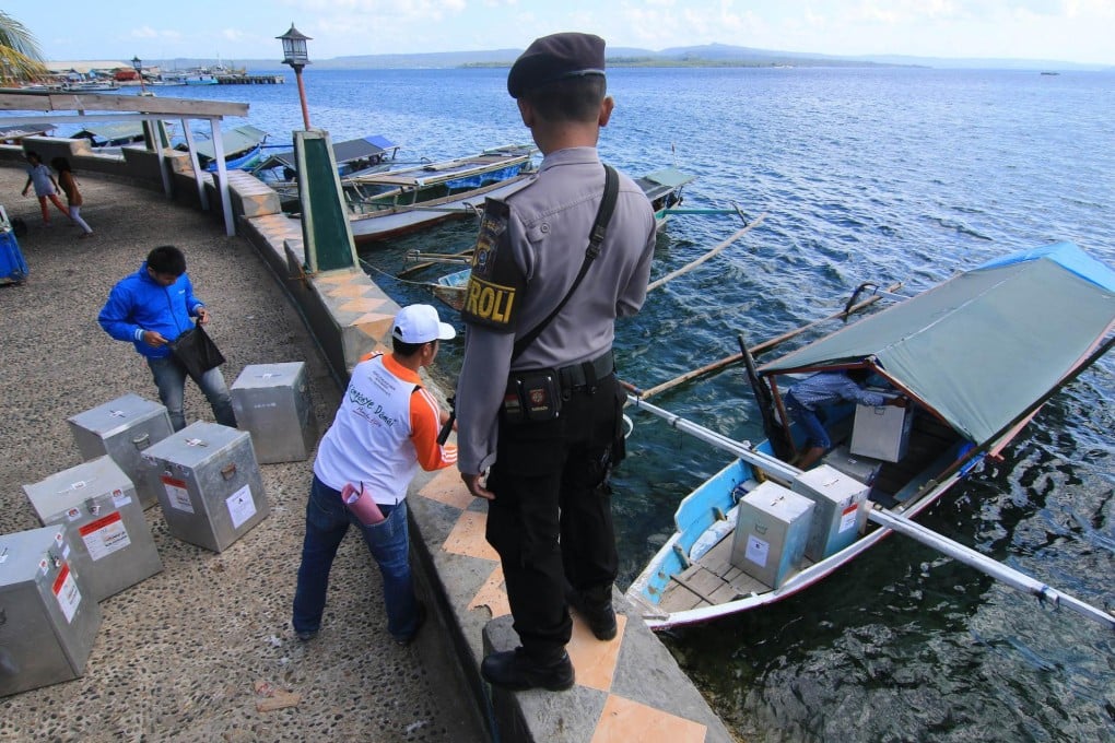 A policeman watches ballot boxes being loaded in Bau-bau in southeast Sulawesi. Photo: AFP
