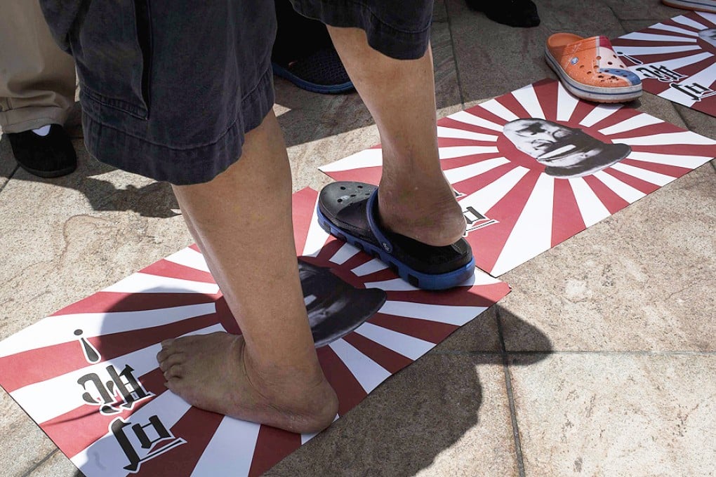A protester steps on illustrations of Japanese military flags featuring a portrait of Hideki Tojo, general of the Imperial Japanese Army and prime minister of Japan during most of World War Two, at a rally against Japanese Prime Minister Shinzo Abe's push to expand Japan's military role abroad, near the Japanese consulate in Hong Kong