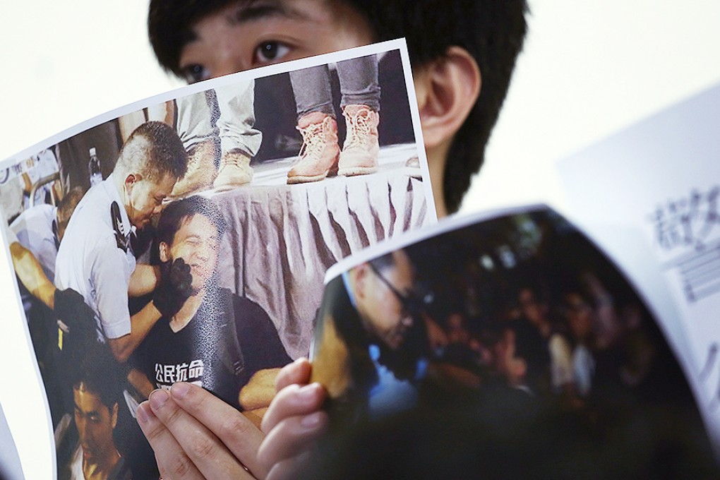 A member of the Federation of Students holds up a photograph of a police officer grabbing a protester's face during the sit-in on Chater Road. Photo: Jonathan Wong