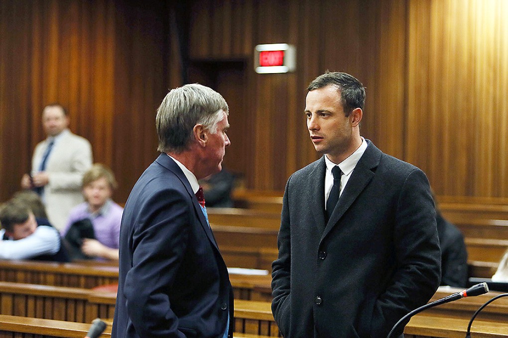 Oscar Pistorius speaks to Brian Webber from his defence team at a court in Pretoria. Photo: AFP
