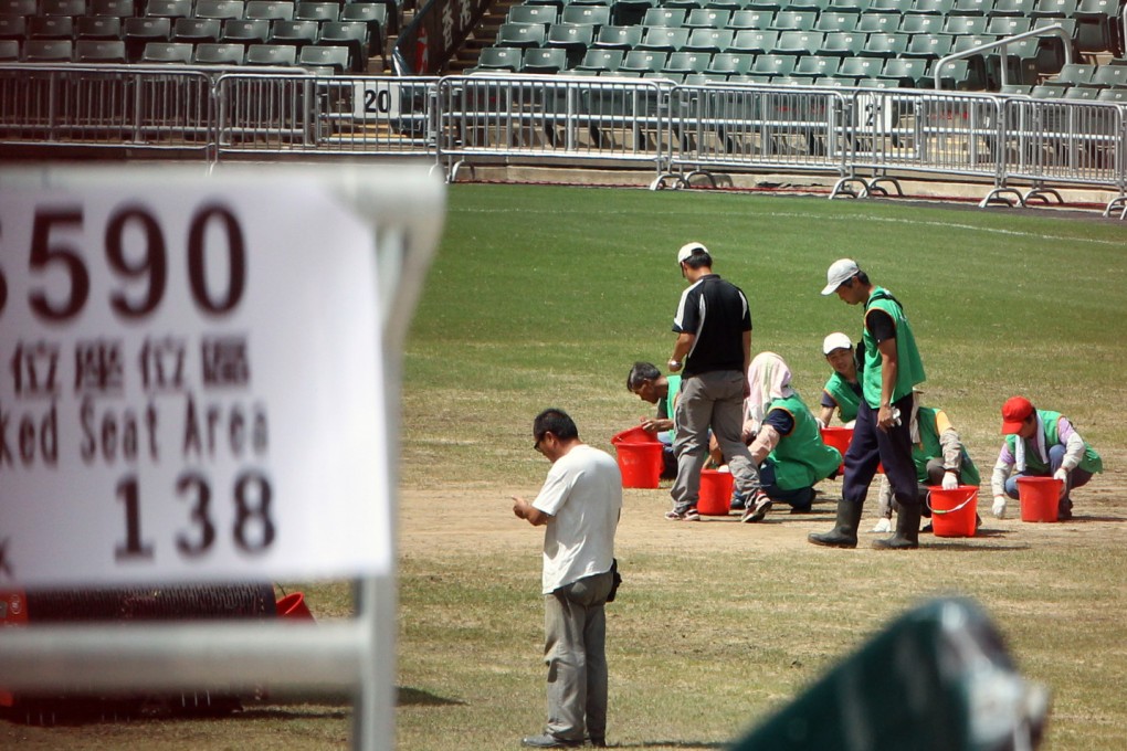 Workers perform maintenance on the turf at Hong Kong Stadium before the match between Kitchee and Manchester United last July. Photo: David Wong
