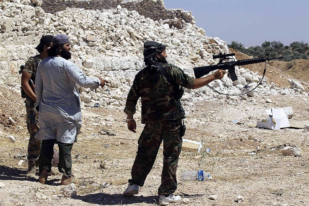 A Free Syrian Army fighter holds up his weapon as he stands with fellow fighters in the southern Idlib countryside. Photo: Reuters
