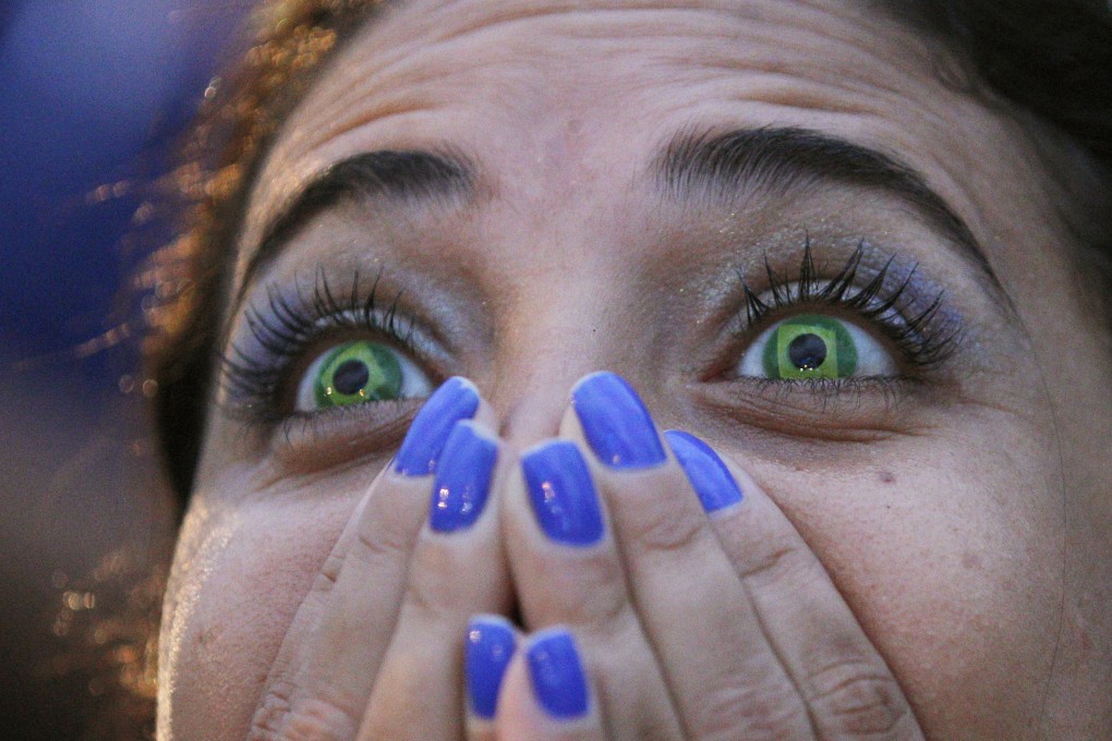 A fan wearing Brazil contact lenses can't believe what she's witnessing. Photo: AP