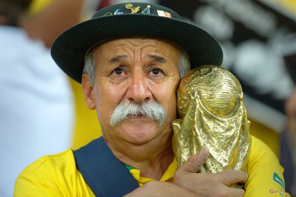 A Brazilian fan clutches a replica of the Fifa World Cup trophy after Brazil are thumped 7-1 by Germany at the Mineirao stadium in Belo Horizonte. Photo: EPA