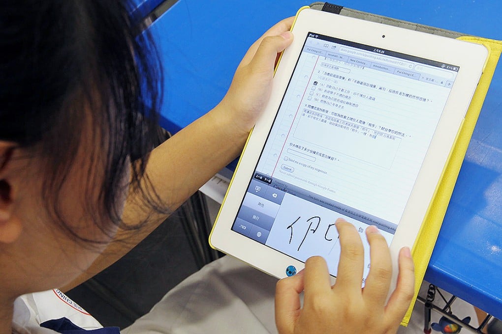 Form 1 student writes comments on iPads in response to items projector. Photo: May Tse