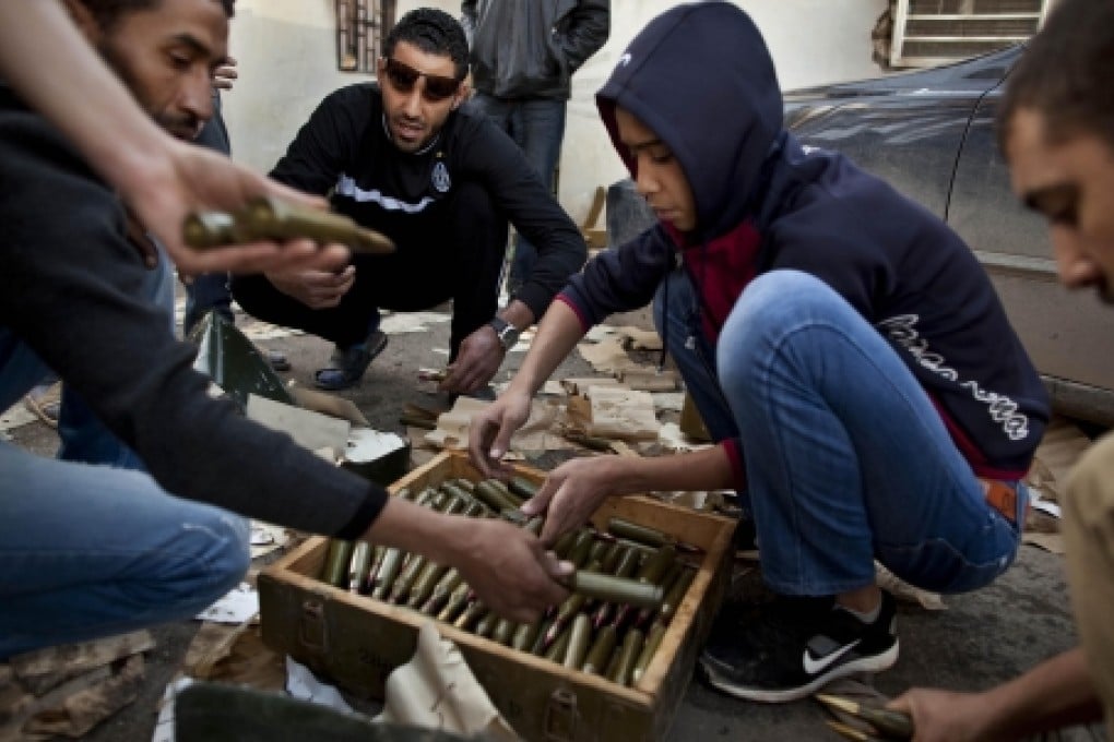 Libyan men distribute arms in a country that has been awash in weapons since the 2011 ouster of strongman Muammar Gaddafi. Heavy weapons explosions were heard this morning in Tripoli. Photo: AP