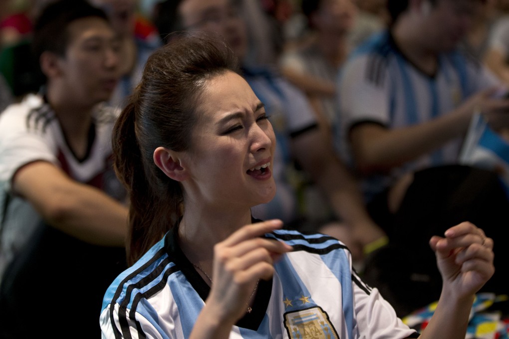 A Chinese soccer fan wearing a Argentina top reacts as she watches the World Cup final. Photo: AP