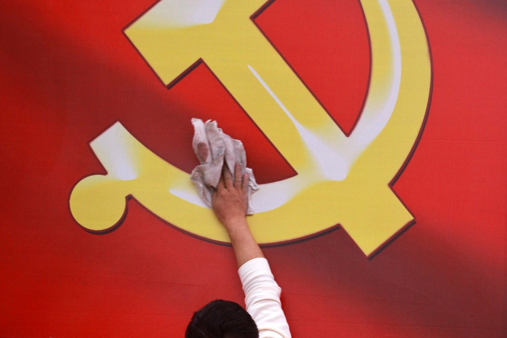 A worker wipes a board showing an emblem of Chinese Communist Party. Photo: AP