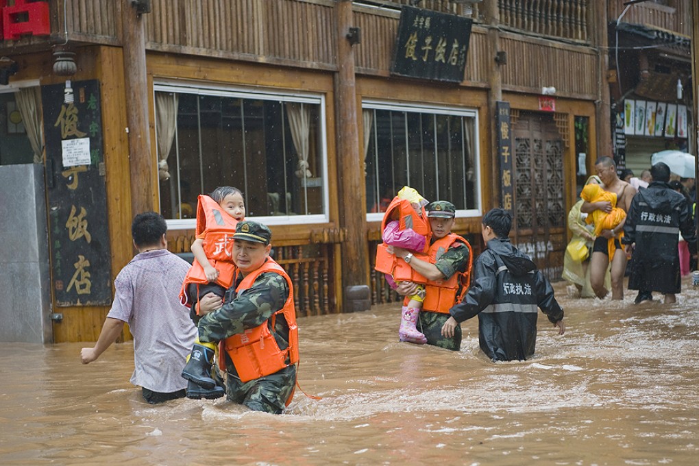 Authorities help evacuate residents and tourists in waist-deep floods. Photo: Xinhua