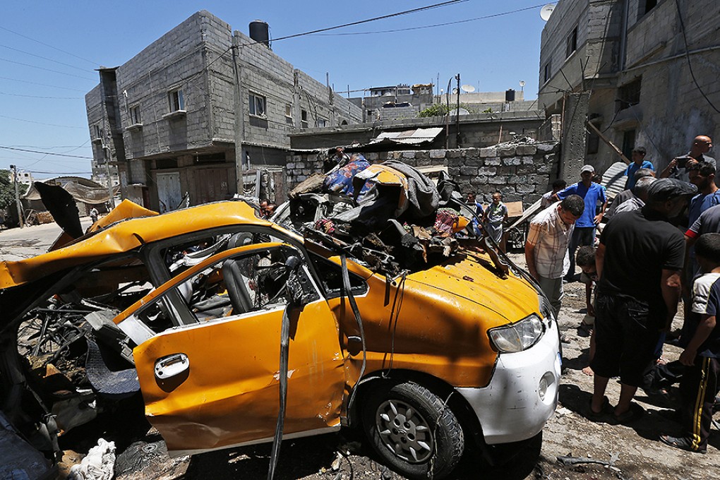 Palestinians gather around a vehicle that was destroyed by an Israeli missile strike in Khan Younis, southern Gaza Strip. Photo: AP