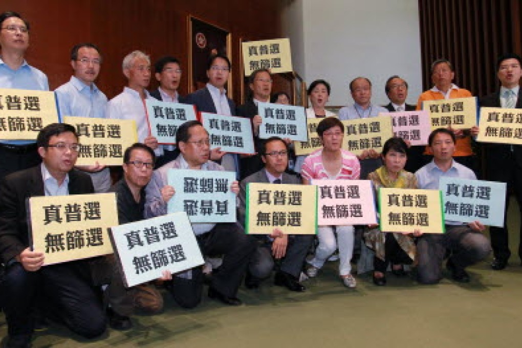 Pan-Democratic lawmakers hold placards to demand universal suffrage during Chief Executive Leung Chun-ying's Question and Answer Session on July 3. Photo: Dickson Lee