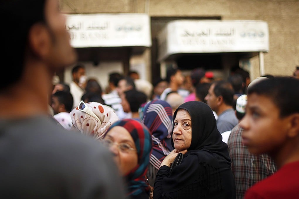 Palestinians wait to withdraw cash from an ATM machine outside a bank in Gaza City. Photo: Reuters