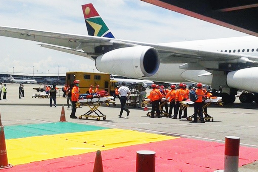 South African Airways flight 286 stands on the tarmac as emergency crews unload the injured passengers. Photo: SCMP