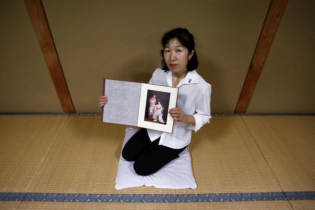 Misa Morimoto shows a photo of herself and her identical twin when they were 20, when she last saw her sister alive. Photo: Reuters