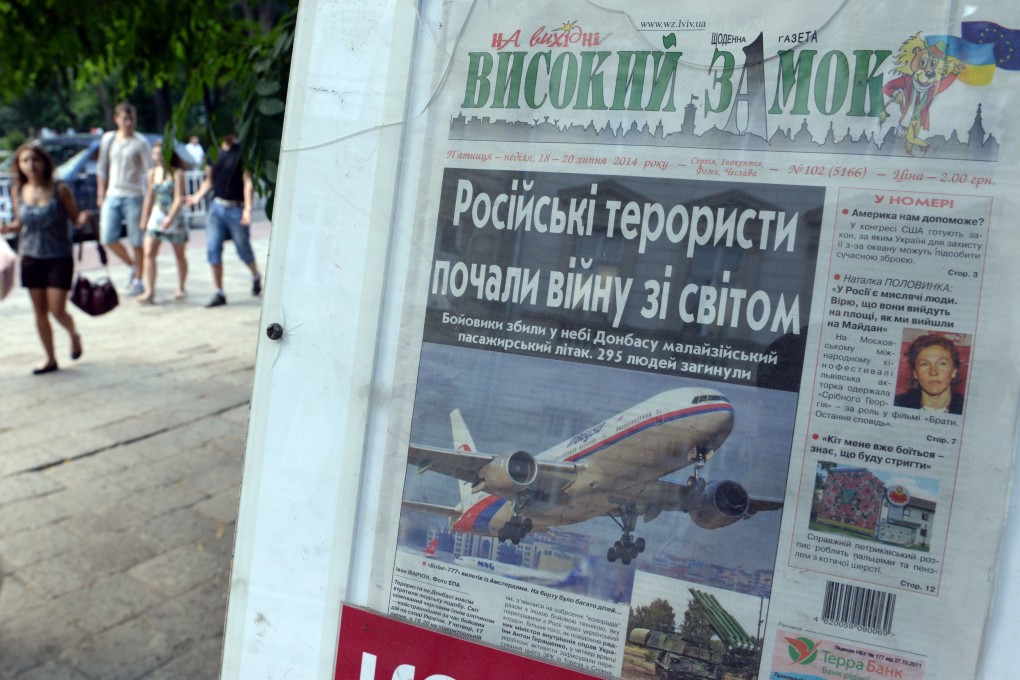 People walk in Lviv, passing a newsstand with newspaper depicting flight MH17. Photo: AFP