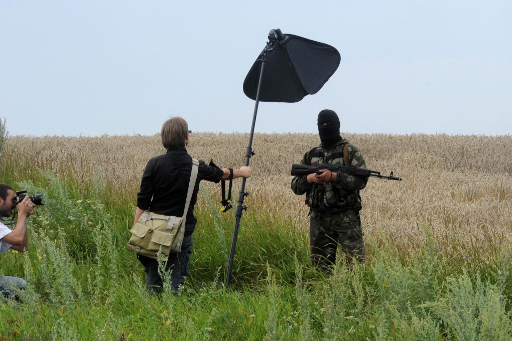 A masked armed separatist poses for a photograph near the site of the crash. Photo: AFP