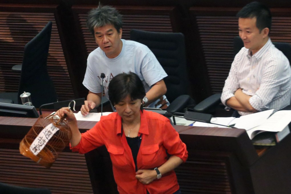 Ann Chiang Lai-wan snatches Leung Kwok-hung's "universal suffrage caged" protest prop during Legco's constitutional affairs panel meeting yesterday. Photo: Felix Wong