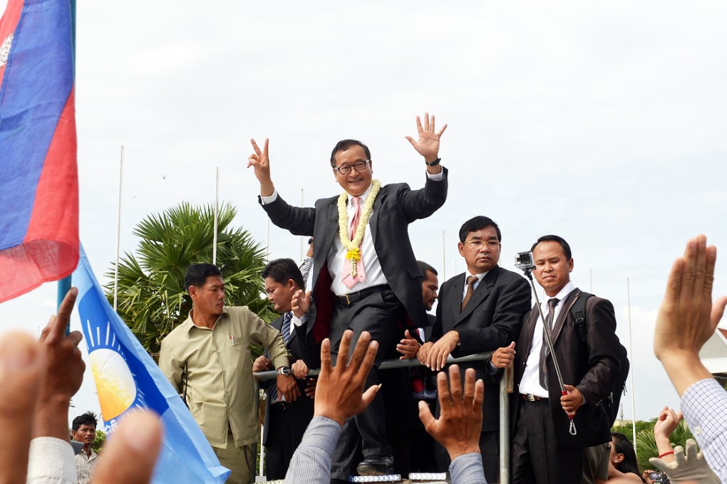 Cambodian opposition leader Sam Rainsy greets supporters on his return from France after eight politicians from his party were arrested and charged with insurrection over a protest that turned violent. Photo: AFP