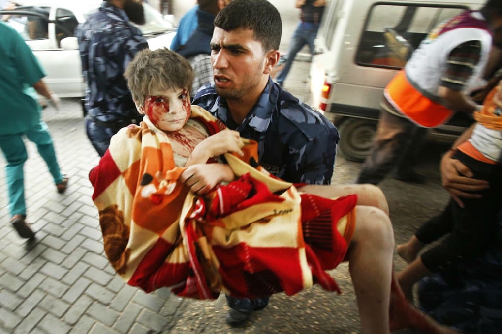 A Palestinian policeman carries a boy, who medics said was wounded in Israeli shelling, at a hospital in Gaza City. Photo: Reuters