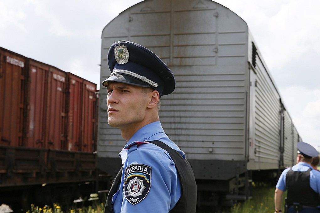 A Ukrainian policeman watches as a train carrying the remains of Malaysia Airlines MH17 victims arrives in Kharkiv. Photo: Reuters