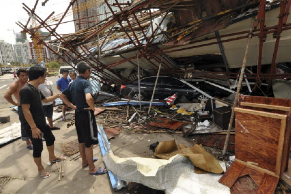 Residents of Haikou, Hainan, look at a vehicle trapped under a collapsed building after Super Typhoon Rammasun, the strongest typhoon in four decades, swept through. Photo: Xinhua