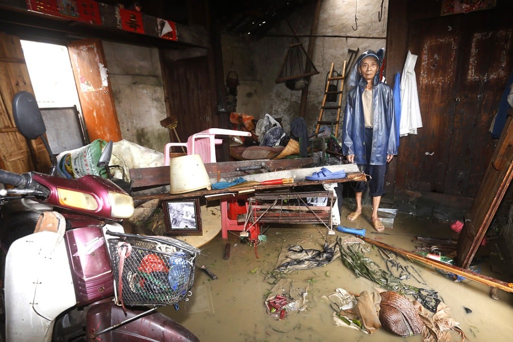 Farmer Huang Youliang stands in his house flooded by Super Typhoon Rammasun near Haikou, Hainan. Photo: EPA