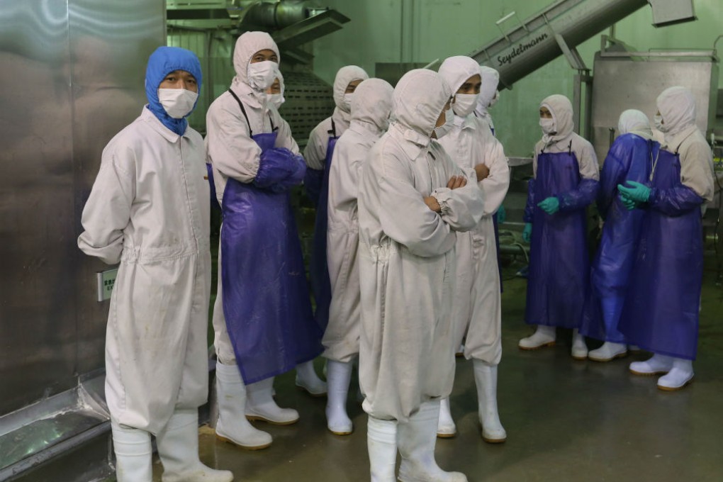Workers stand aside as inspectors investigate the Shanghai Husi Food Company. Photo: AFP