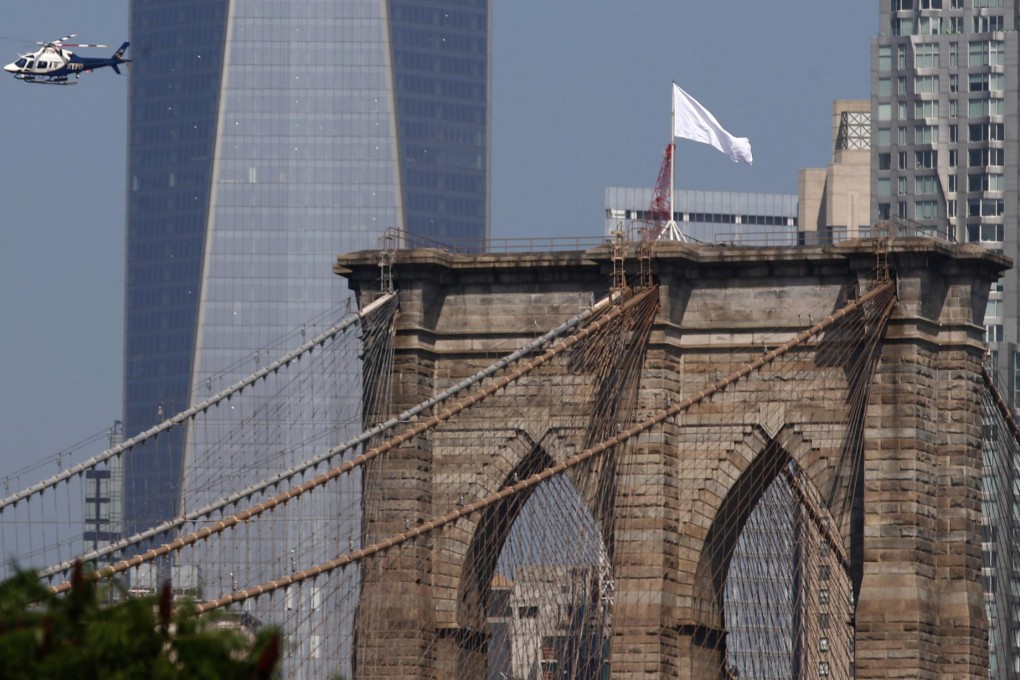 A New York Police Department helicopter flies over the Brooklyn Bridge inspecting the white flags that had replaced the American flags that had been on top. Photo: EPA