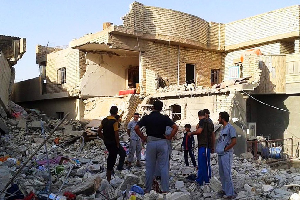Iraqis stand in the debris of a house after an an air raid by the Iraqi Air Force in Fallujah city. Photo: EPA
