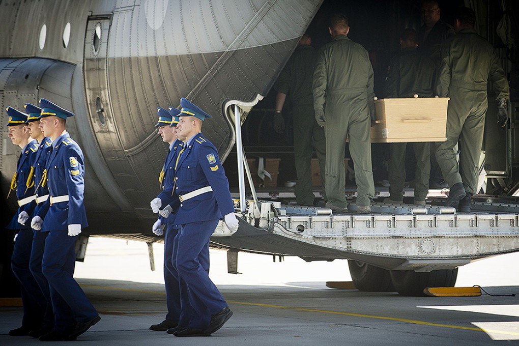Ukrainian soldiers carry coffins with the remains of victims of the MH17 crash to a military plane during a ceremony at the airport of Kharkiv. Photo: AFP