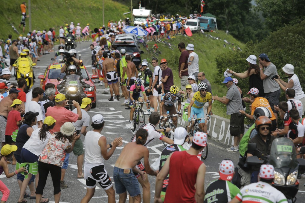 Spectators cheer as Italy's Vincenzo Nibali, wearing the overall leader's yellow jersey, France's Jean-Christophe Peraud and Croatia's Kristijan Durasek climb towards Saint-Lary during the 17th stage of the Tour de France. Photo: AP