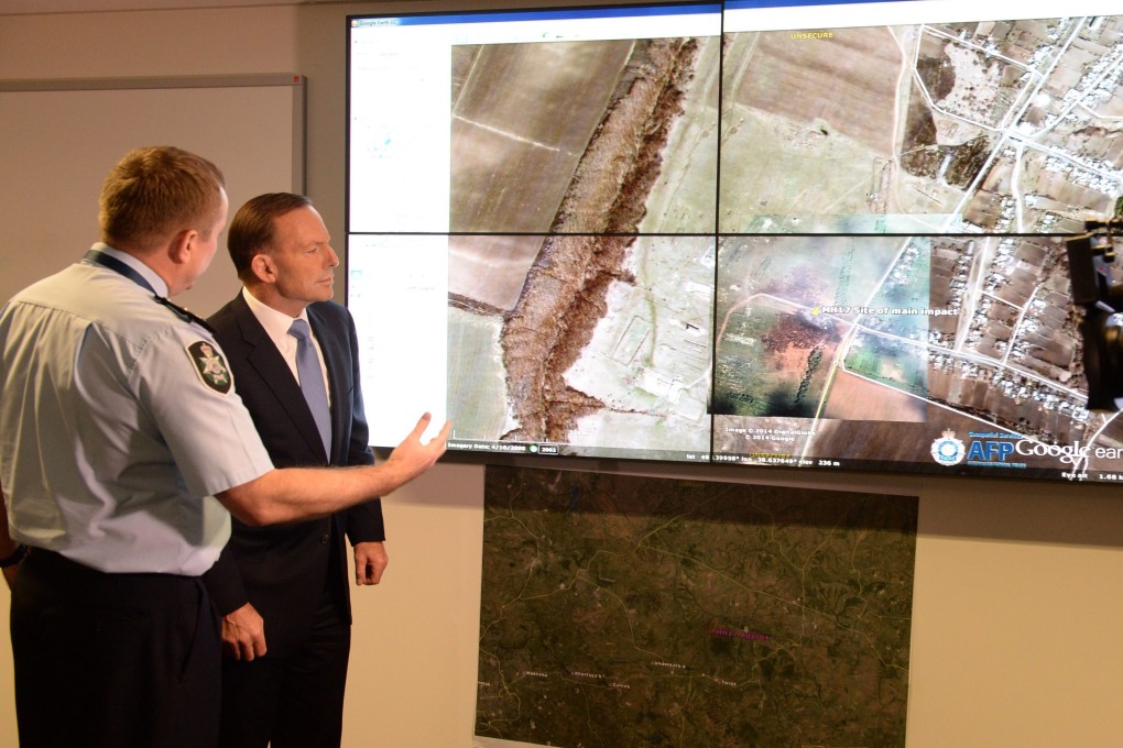 Assistant Australian Federal Police commissioner Michael Outrim (left) shows Australian Prime Minister Tony Abbott an aerial view of the MH17 crash site in Canberra on Friday. Photo: EPA