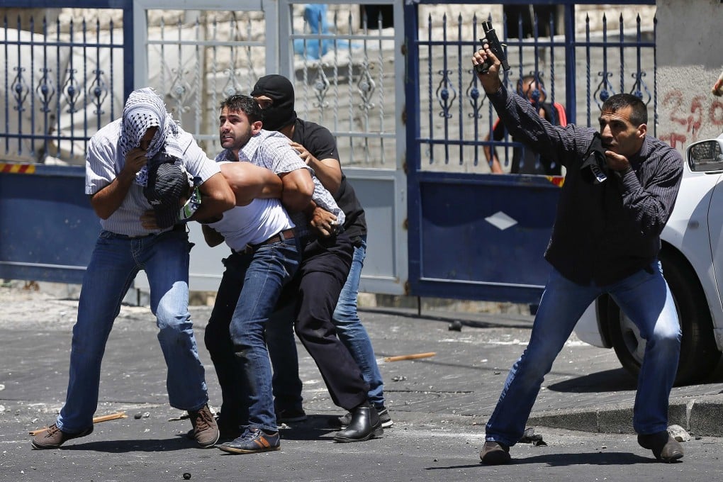 An undercover Israeli police officer holds a gun in the air as colleagues detain a Palestinian in East Jerusalem yesterday. Photo: Reuters