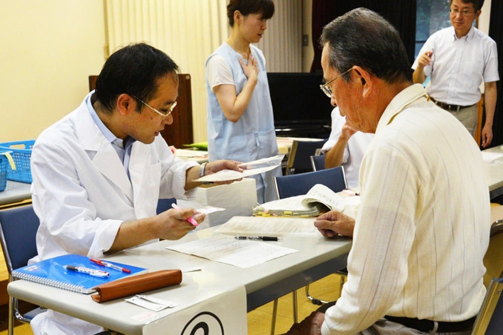 A local resident receiving a dose of iodine tablets from a Kagoshima prefectural officer in the city of Satsumasendai, Kagoshima, Kyushu. Photo: AFP