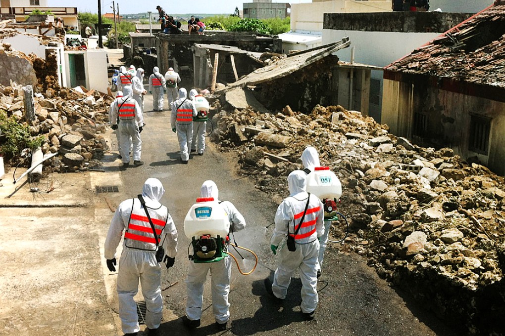 Investigators unseal the crash site at Xixi village, Penghu, yesterday, while soldiers in protective gear spray the area with disinfectant. Photo: CNA