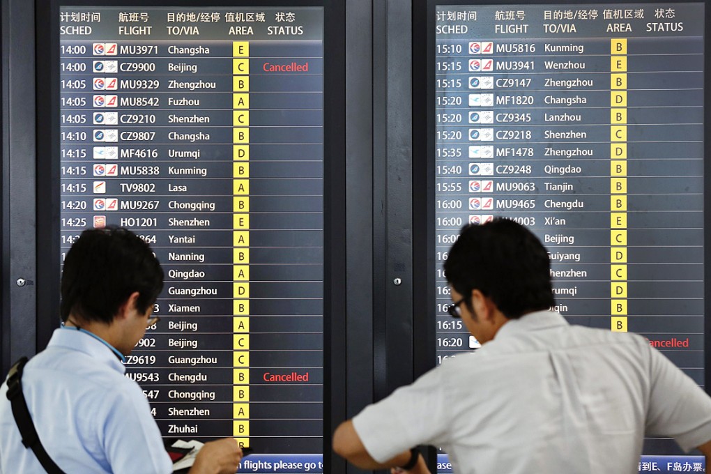 Passengers stand in front of an electronic board displaying flight information at Hongqiao International Airport in Shanghai. China's Air Traffic Management Burea issued a red alert, the highest warning level for airport travel conditions, indicating many flights will be delayed or cancelled. Photo: Reuters