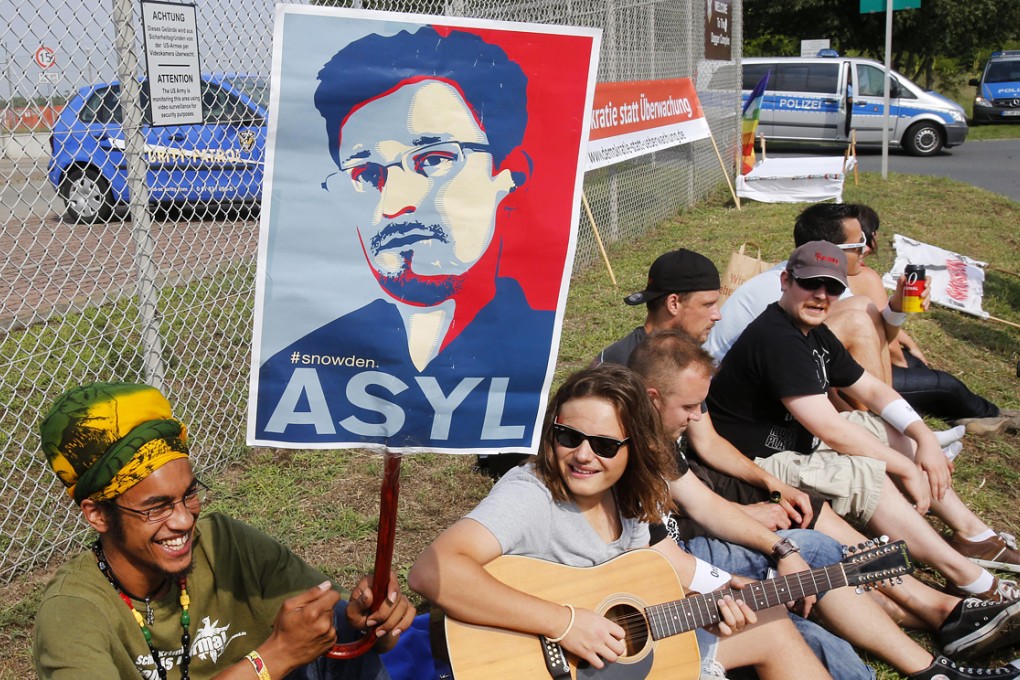 A demonstrator against spying holds a sign asking for asylum for former NSA contractor Edward Snowden outside US Army's 'Dagger Complex' near Griesheim, Germany. Photo: AP