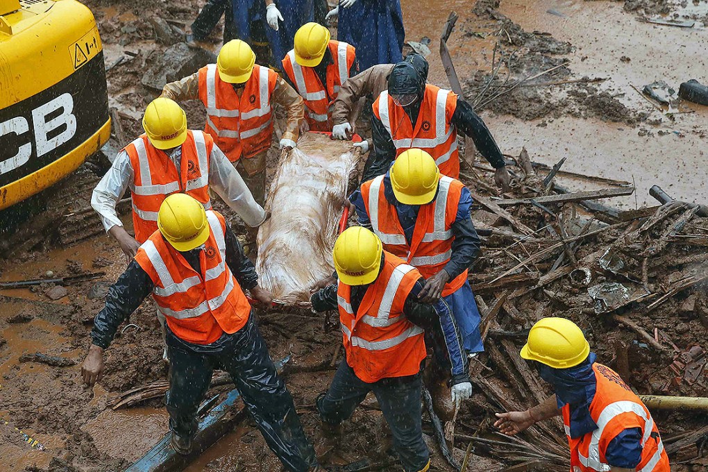 Rescue workers carry the body of a victim from the site of a landslide in Malin. Photo: Reuters